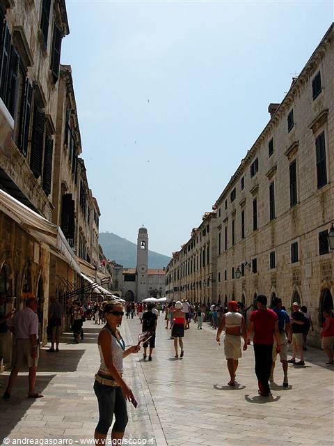 Tourists stroll along Stradun in Dubrovnik, pale stone paving and bell tower