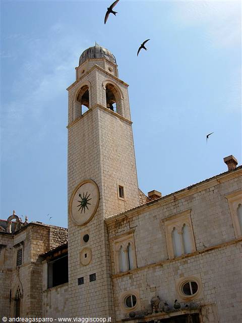 Stone bell tower with clock and swallows flying, Dubrovnik