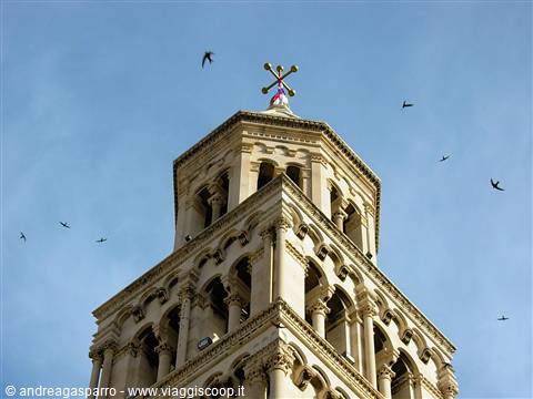 Romanesque bell tower of Split Cathedral against blue sky with flying swallows