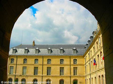 Yellow classical building with French flag framed by a stone arch