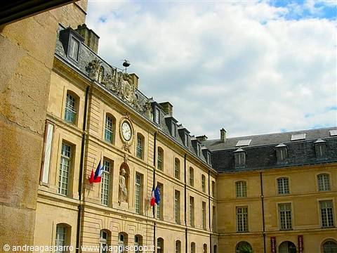 Stone facade of the Hôtel des Invalides in Paris with clock and tricolor flags