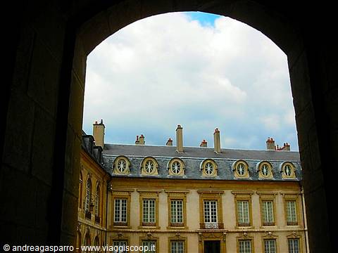 Prince's Palace of Monaco framed by a dark arch, bright clouds above