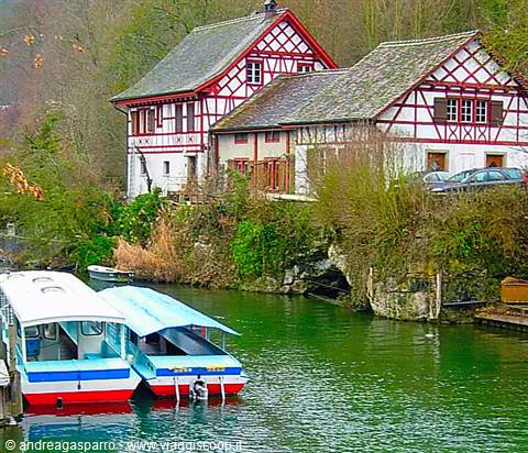 White and blue tourist boats moored on the river in front of red half-timbered houses