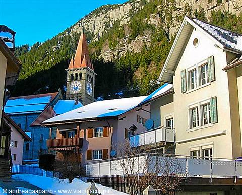 Snowy houses and church bell tower beneath the mountains in the alpine village