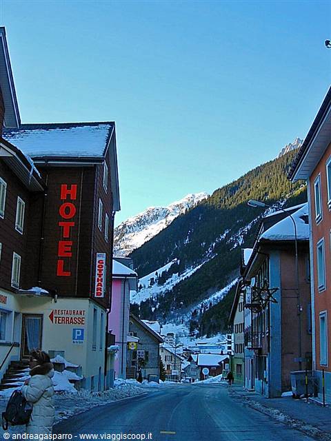 Backpacker outside the snowy Gotthard hotel on an alpine street in Andermatt