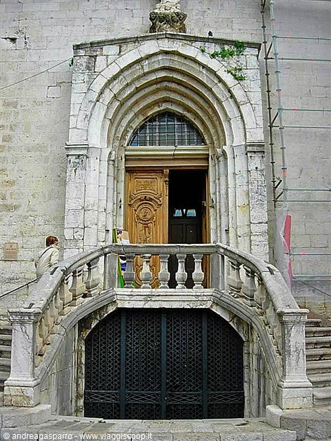 Woman climbs the stone staircase toward the gothic marble portal of a church