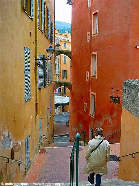 Woman in coat descending stairs between ochre and orange houses, old town