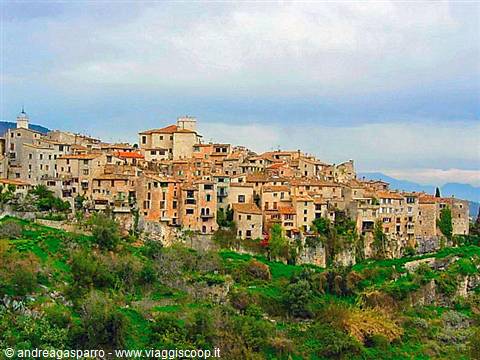 Medieval stone village perched on a green hill under cloudy sky
