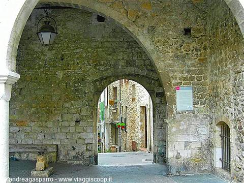 Stone archway with hanging lantern opening onto a medieval alley