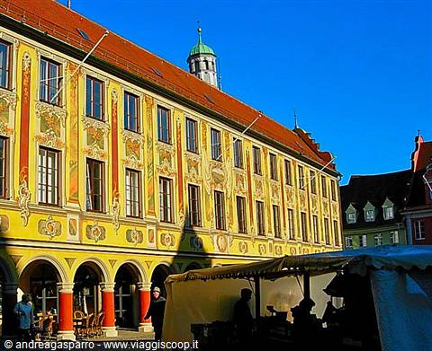 Lindau's painted Old Town Hall, yellow facade in sunlight, market stalls below the arcades