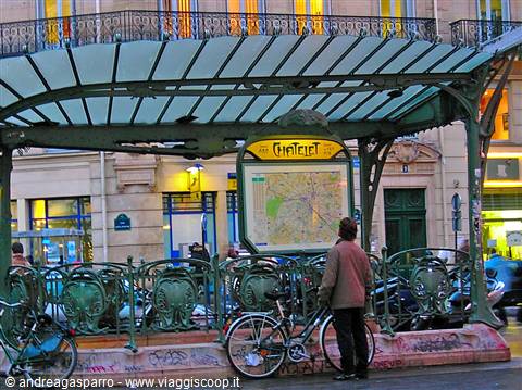 A man with a bicycle stands before the Art Nouveau Cité metro entrance in Paris
