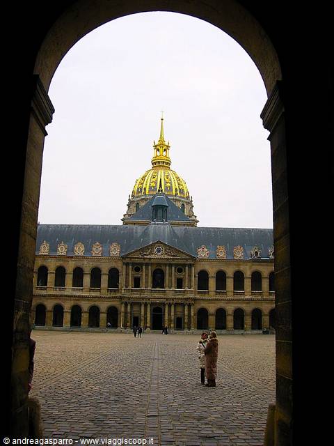 The Hôtel des Invalides golden dome framed by an arch, two women on cobblestones