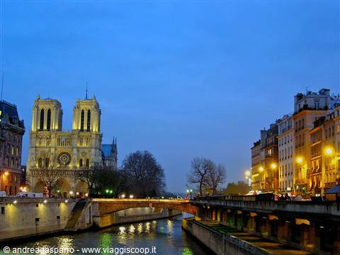 Illuminated Notre-Dame Cathedral by the Seine, bridge and evening lights in Paris