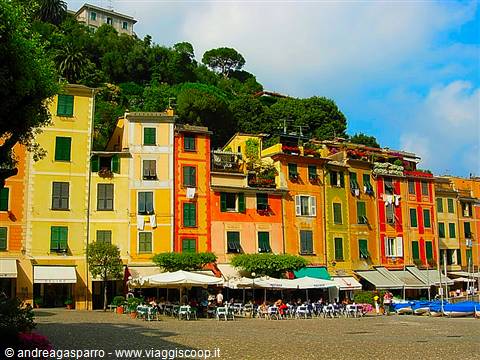 Colorful houses on Portofino's small square, café umbrellas, moored boats