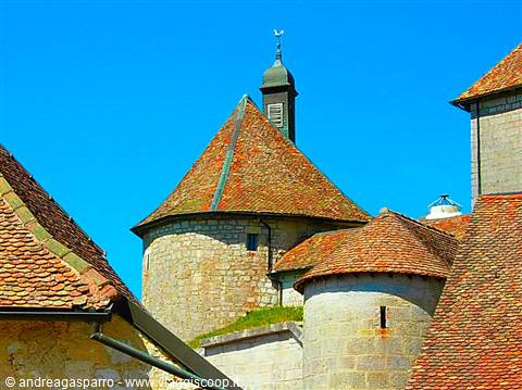 Round stone towers with tiled roofs, medieval fortress under blue sky
