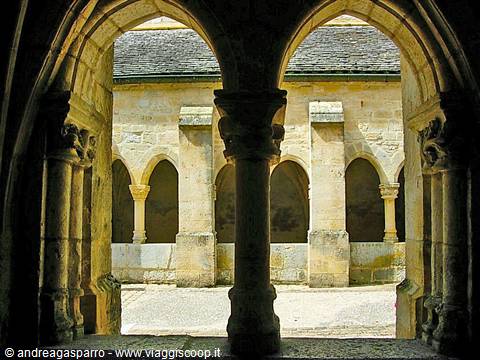 Romanesque stone cloister with paired columns and carved capitals under arches