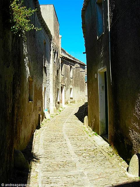 Cobbled alley between old stone houses under bright sunlight