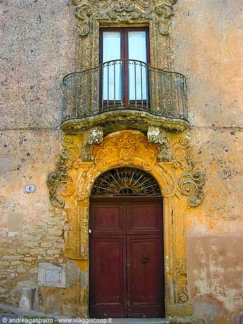 Baroque stone portal in golden hue with wrought iron balcony above the door