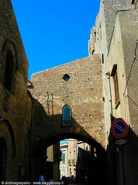 Medieval stone arch over a shaded alley between old buildings