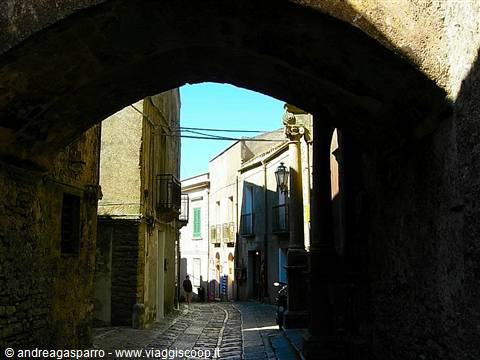 Stone arch over cobbled alley with old sunlit houses