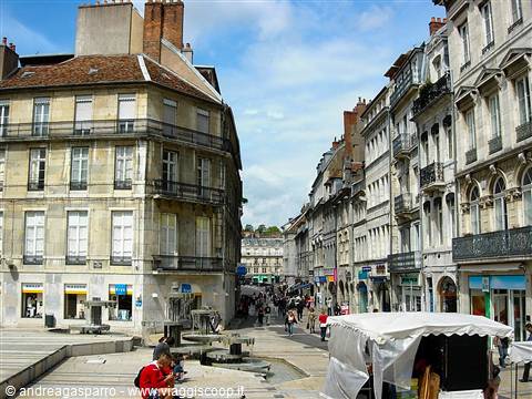 Pedestrian square with fountain and market stalls among old French buildings