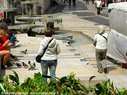 Passersby and pigeons near the fountains of a Zagreb square