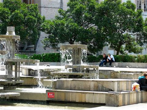 Multi-tiered stone fountain with cascading water, people sitting on the steps