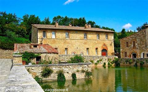 Bagno Vignoni: old stone buildings reflected in the green thermal pool