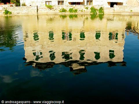 Stone building with green windows reflected in the calm river water