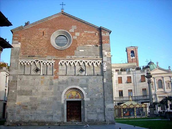 Romanesque stone and brick facade with round window, carousel nearby