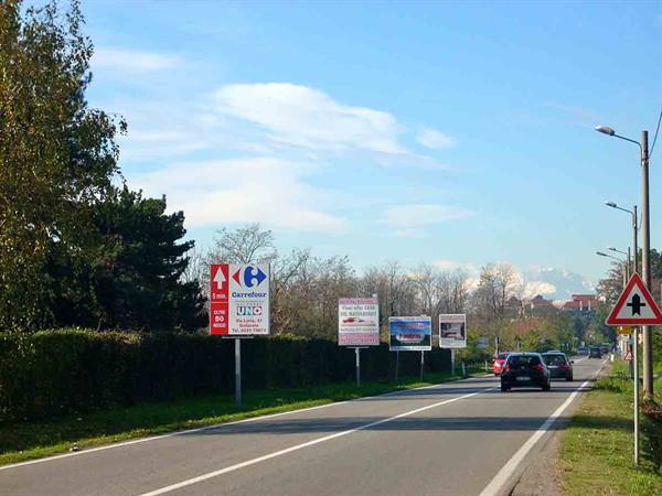cars on a suburban road lined with advertising billboards and road signs