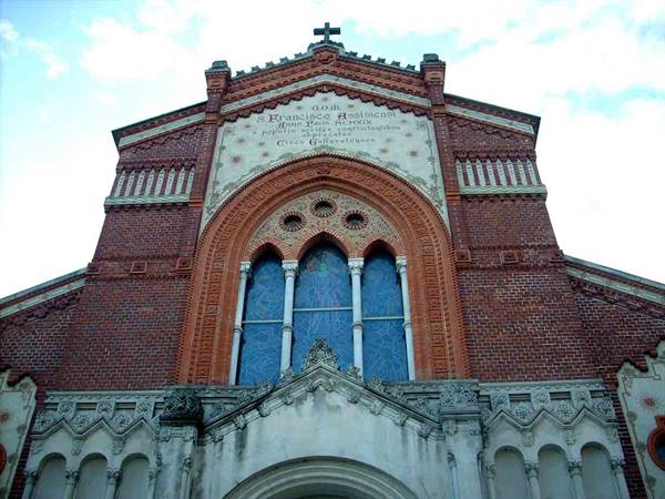 Red brick facade of San Francesco church in Asiago against a cloudy sky