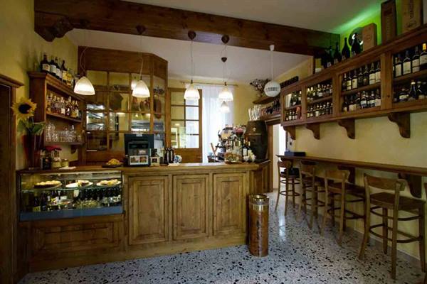 Wooden bar counter with bottles, stools and warm hanging lamps