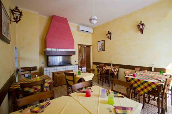 Dining room with set tables, yellow tablecloths and a pink-painted fireplace