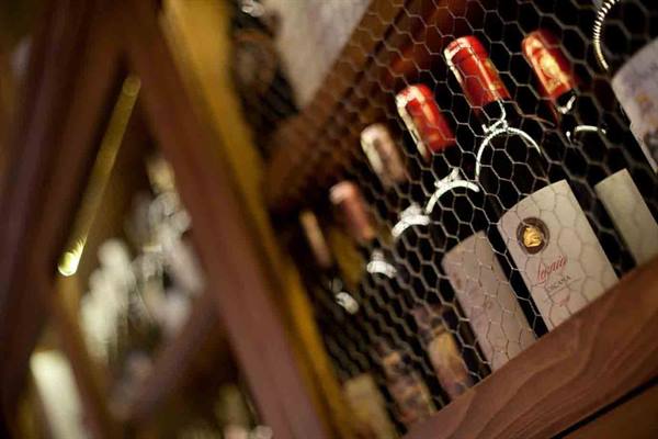Wine bottles behind wire mesh on a wooden shelf
