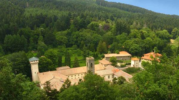 Stone monastery with bell tower nestled in the green Camaldoli forest