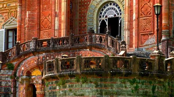 Stone balustrade and red brick façade before an ornate portal, Rocchetta Mattei