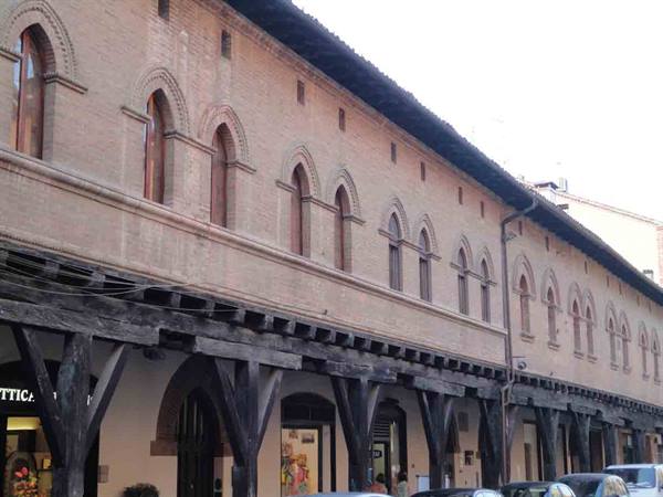 Brick building with Gothic mullioned windows and wooden-beam portico in Bologna
