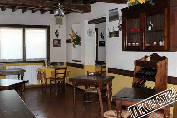 Rustic dining room of La Vecchia Osteria with wooden tables and wine bottles