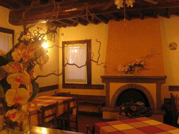 Trattoria dining room with brick fireplace, wooden beams and yellow orchids