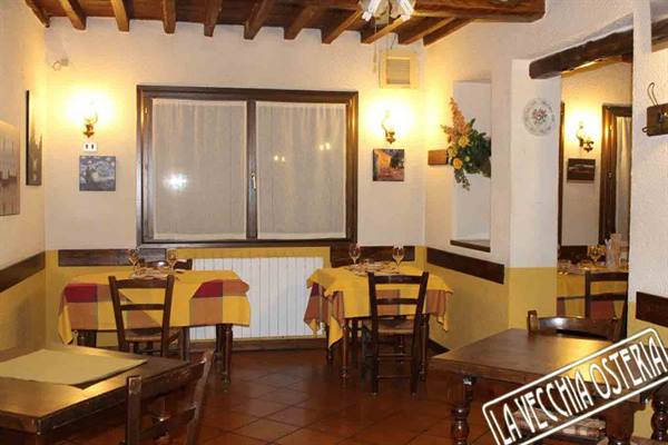 Rustic dining room at La Vecchia Osteria inn, tables set with yellow tablecloths