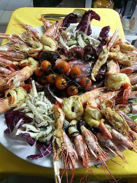 Seafood platter with prawns, octopus, calamari and cherry tomatoes on yellow tablecloth