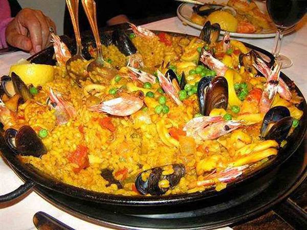 Seafood paella in the black pan, with prawns, mussels and peas