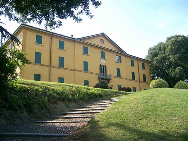 Yellow villa with green shutters, stone steps across the lawn