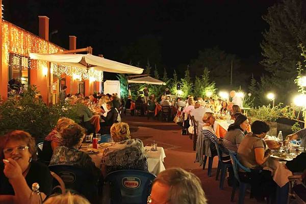 Outdoor restaurant at night, diners at tables under string lights and umbrellas