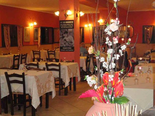 Restaurant dining room with set tables, orange walls and artificial flower vase