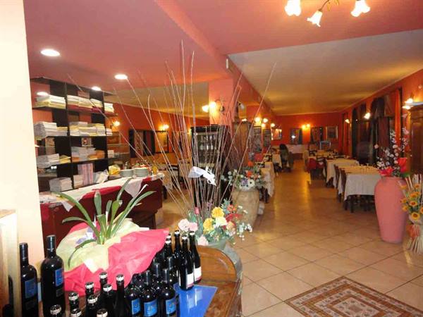 Restaurant dining room with orange walls, wine bottles in foreground and set tables