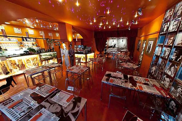 Tables with paper placemats in an orange bar with movie-star photos on walls