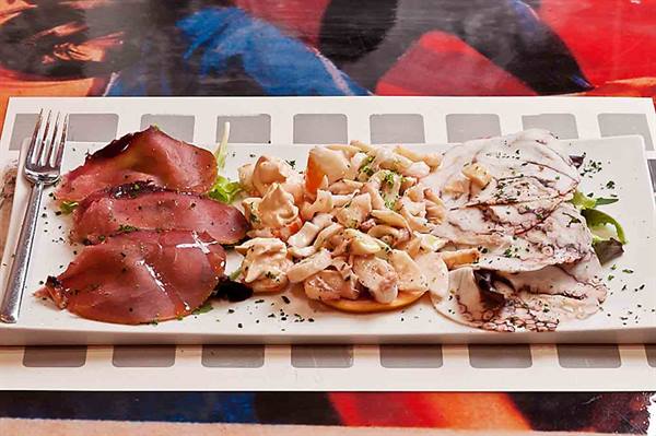Mixed appetizer with bresaola, octopus and seafood salad on white plate