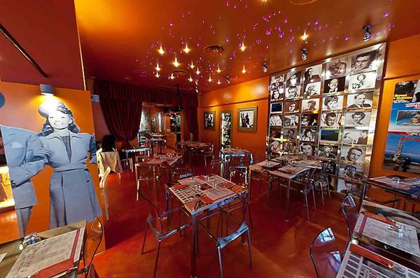Restaurant dining room with orange walls, set tables and Hollywood star photos
